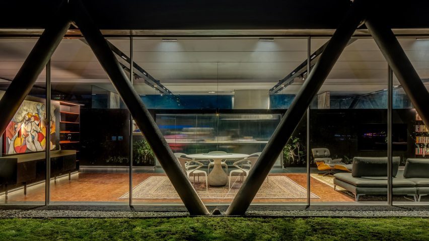 Exterior of a home with a steel structure and glazed walls revealing an open-plan living space