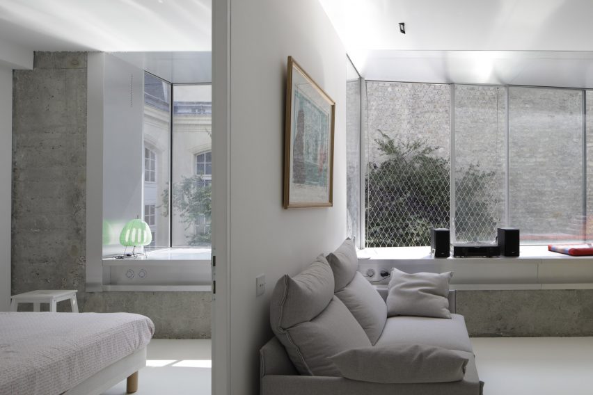 Partition wall dividing a living room with a grey sofa and a bedroom