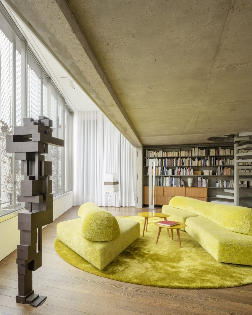 Lime green sofa seating on a rug next to a window with a bookshelf behind