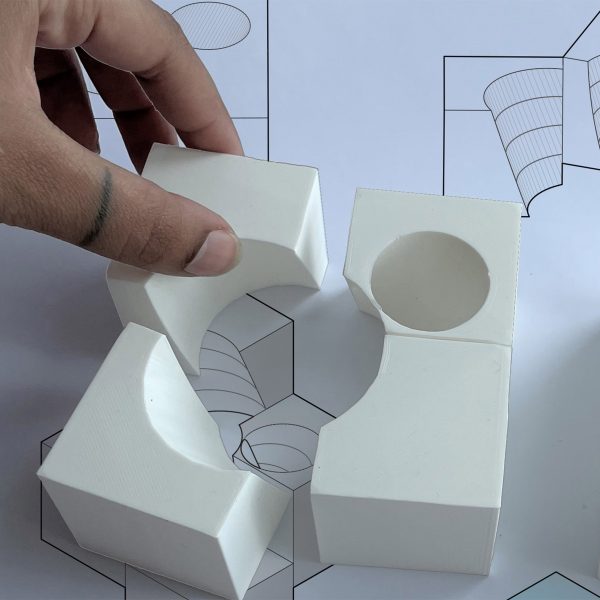 A hand assembling parts of a white, curved architectural model
