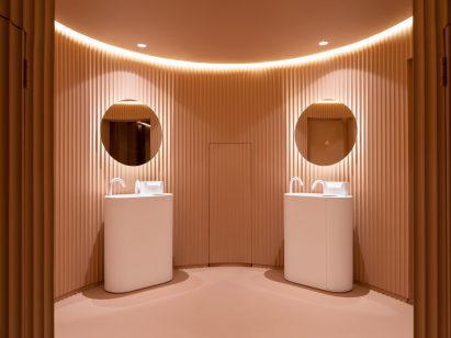 Peach public bathroom interior with two freestanding sinks and circular mirrors