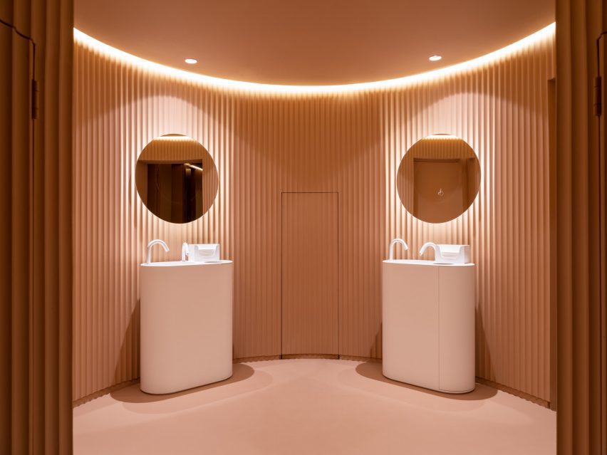 Peach public bathroom interior with two freestanding sinks and circular mirrors