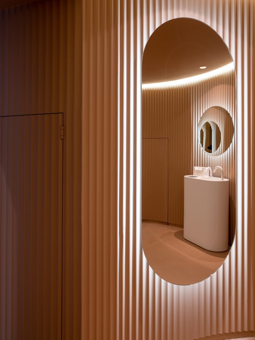 Peach ribbed wall panelling with an elogated backlit wall mirror