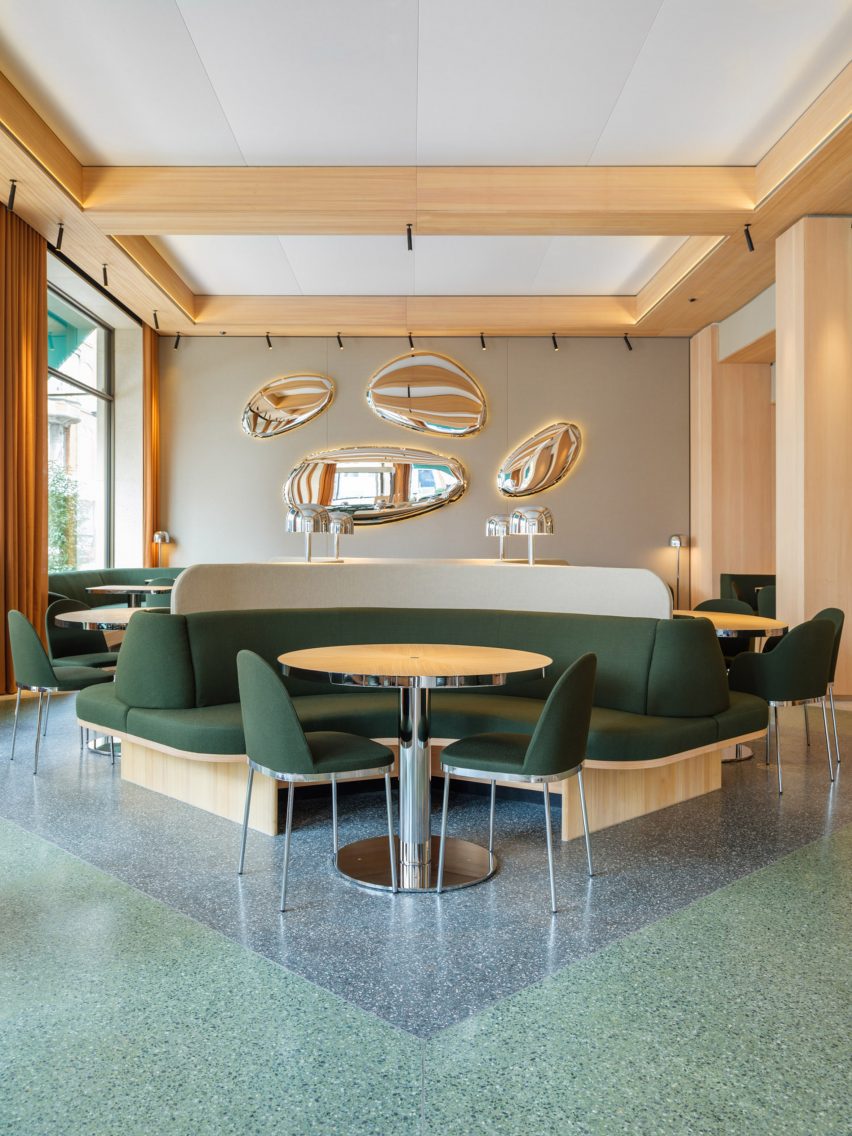 Restautant interior with green upholstered seating and wood tables