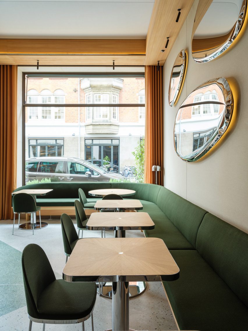 Restautant interior with green upholstered seating and wood tables