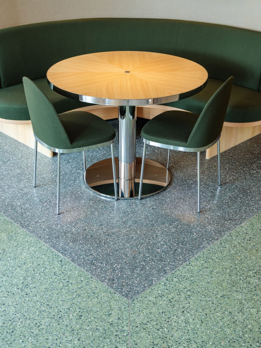 Restautant interior with green upholstered seating, wood tables and terrazzo flooring