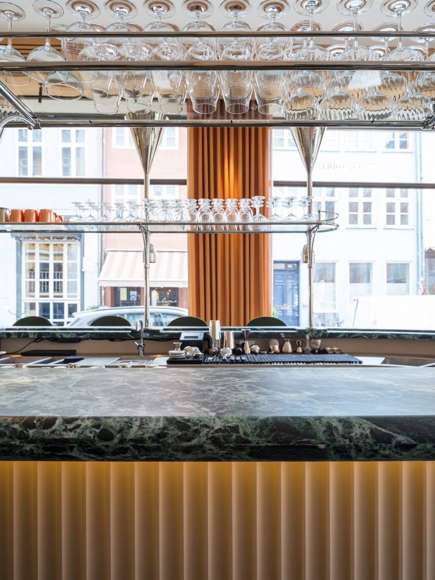 Restaurant bar with green marble countertop and stainless steel glass rack