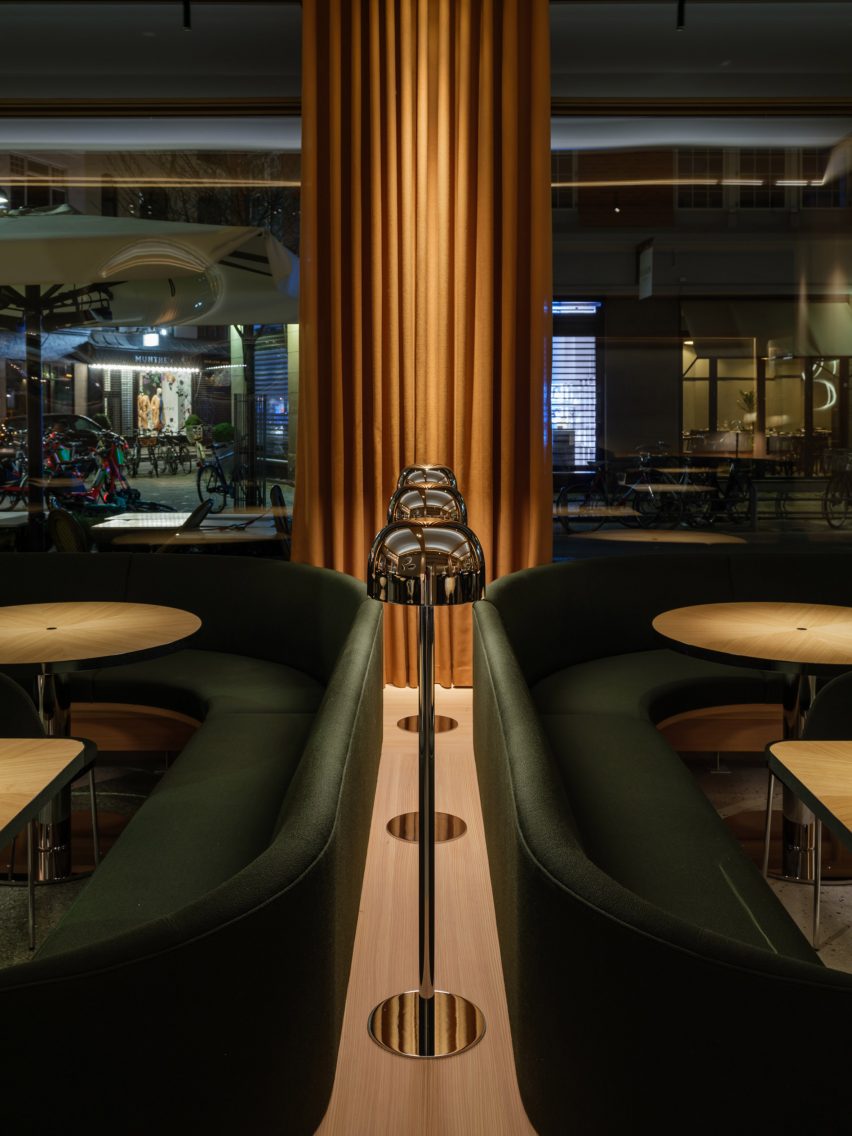 Restautant interior with green upholstered seating and wood tables