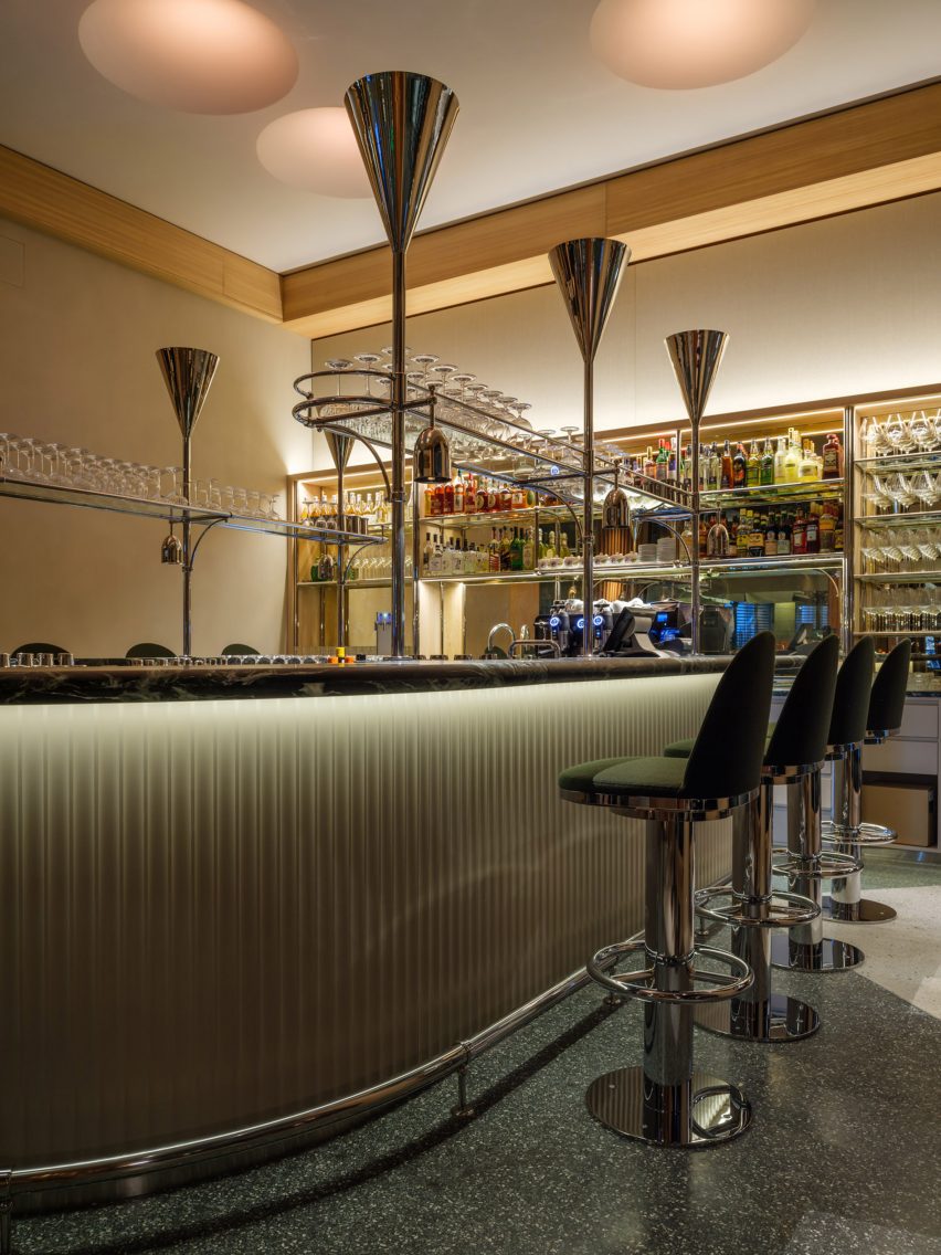 Restaurant bar with silver conical uplights and green bar stools