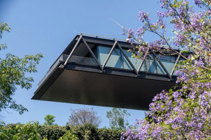 Black metal cantilevering home over bushes