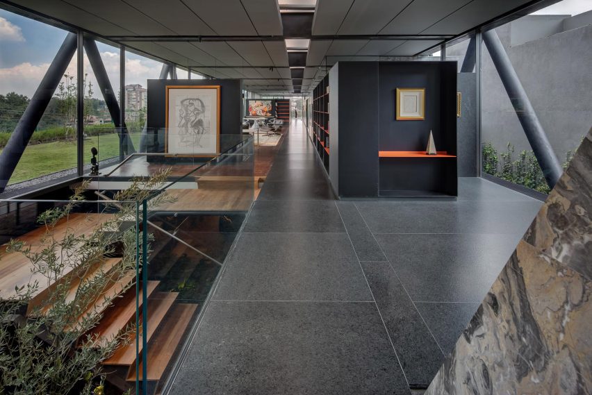 An open space with granite floors and a timber staircase leading to a basement