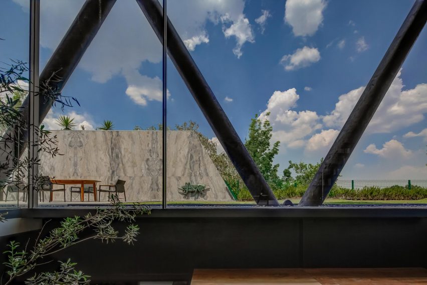 Large windows looking out to the exterior steel structure of a home and outdoor garden