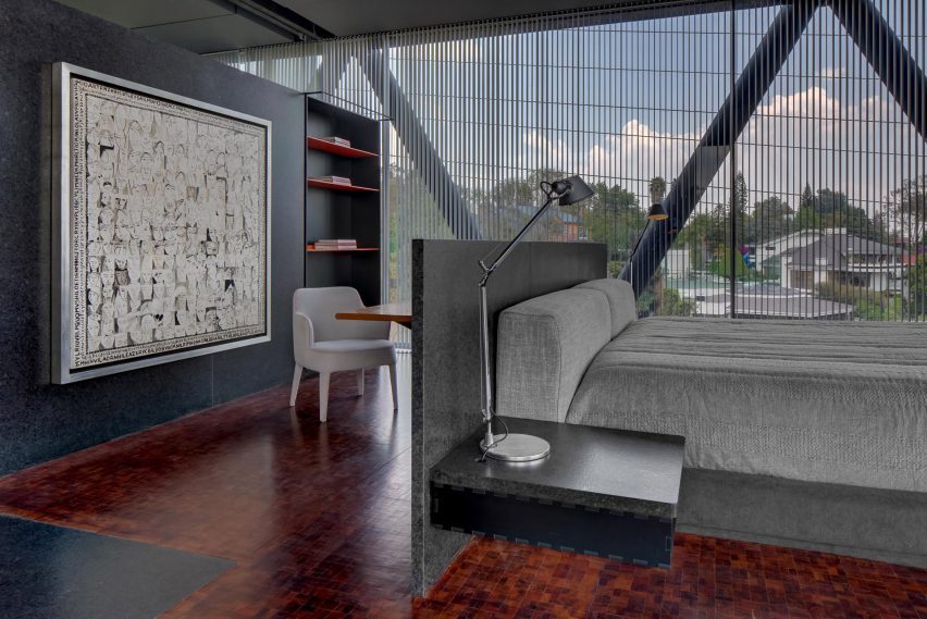 A bedroom with a grey bed and dark marble partition walls and furniture
