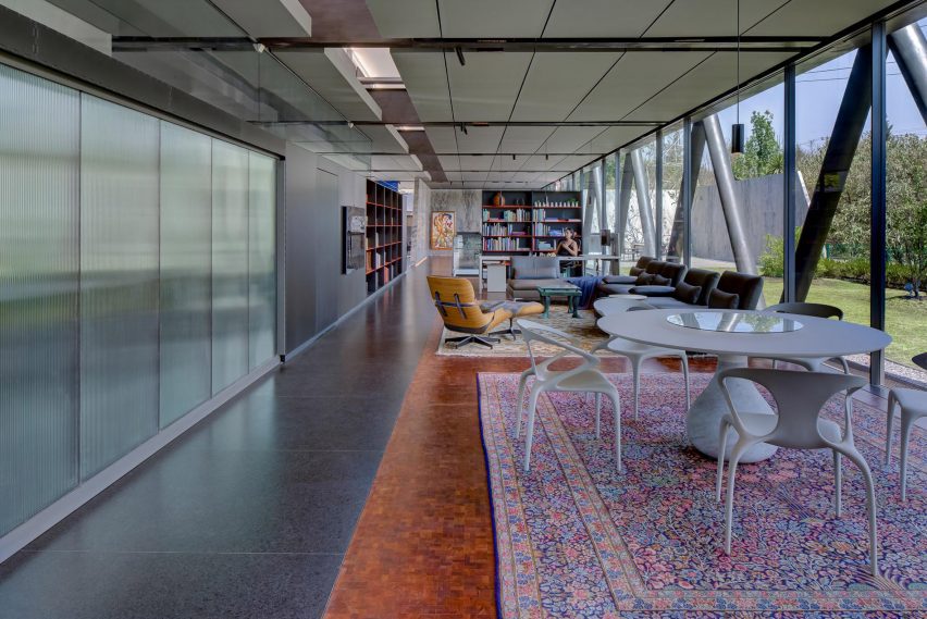 Open-plan living space with granite floors, persian rugs and a white circular table with chairs