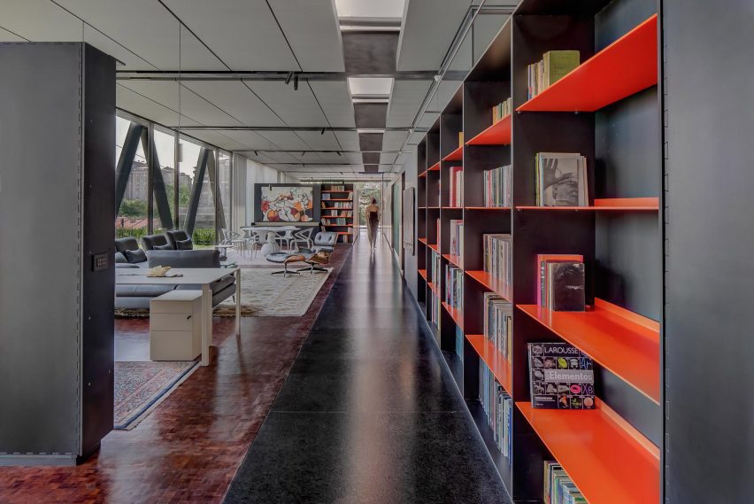 Interior of an open-plan living space with granite floors, red bookshelves and grey seating
