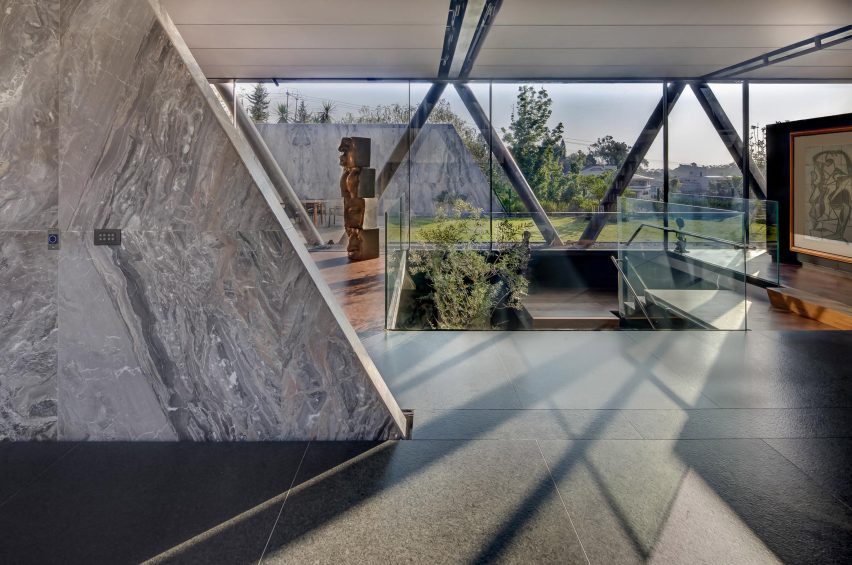 Interior space with granite floors, slanted marble partition wall and glazed wall overlooking a garden