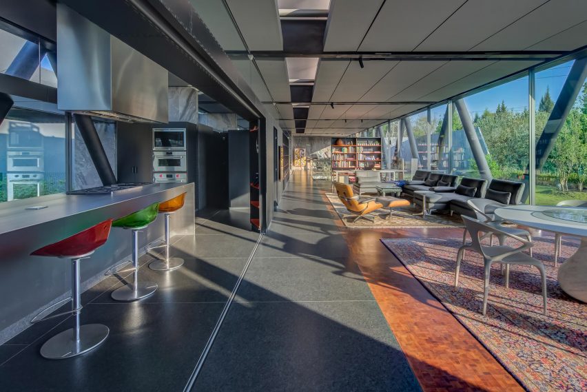Open-plan living space with granite floors and a persian rug, and a kitchen separated by a sliding door
