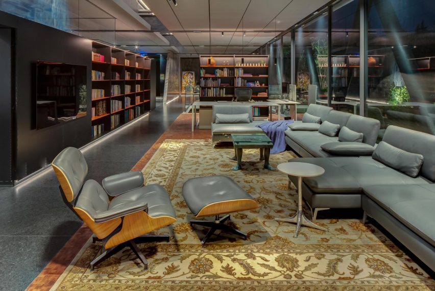 Open-plan living space with granite floors, persian rug, grey sofa and lounge chair with an ottoman