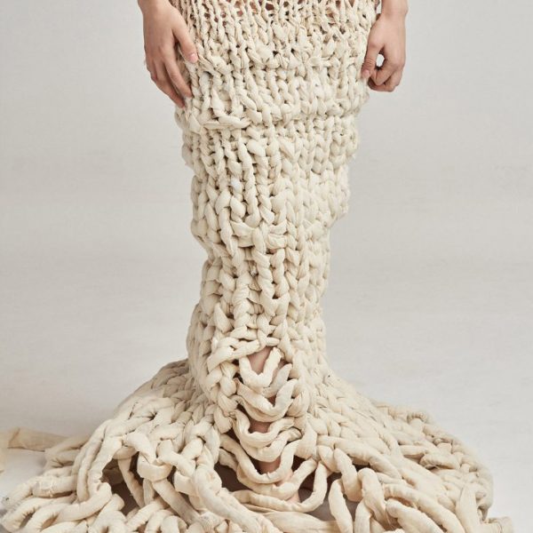 Photograph of model wearing neutral-coloured unravelling garment