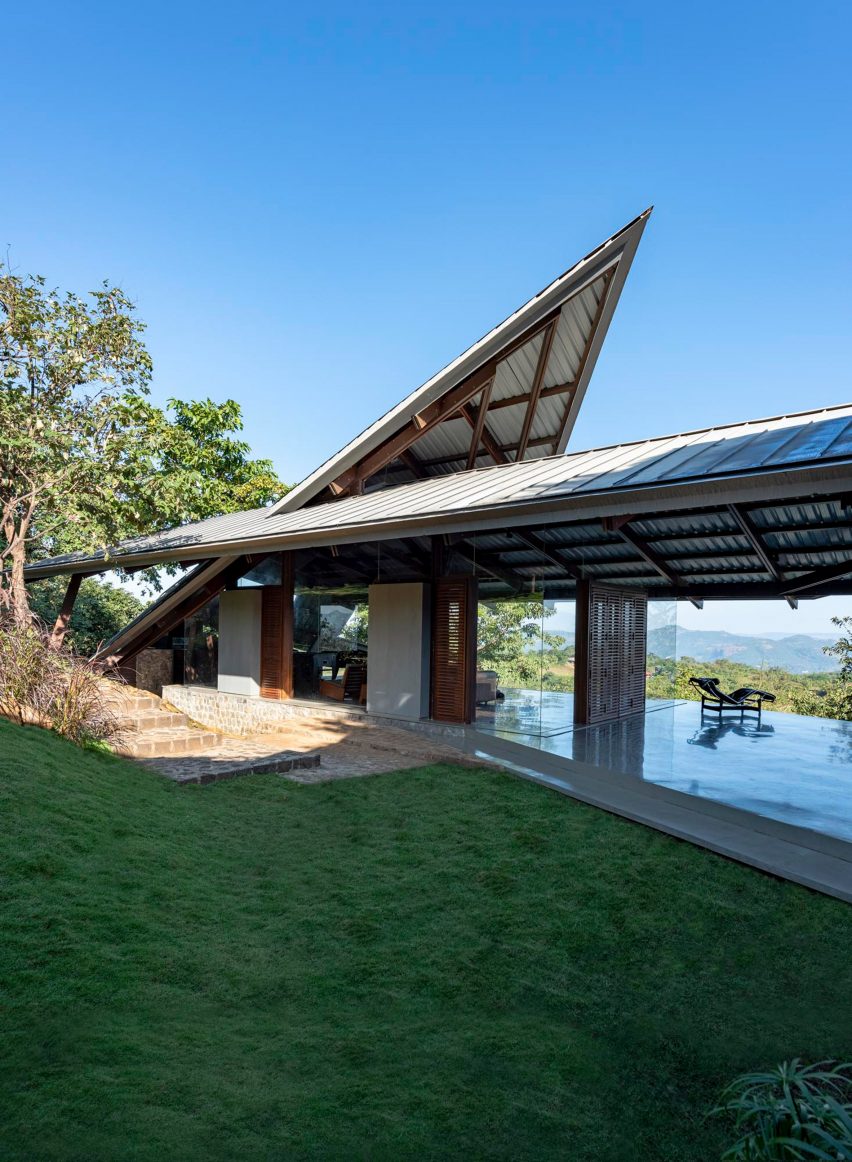 Exterior of a home in India with a jagged metal roof and grass garden