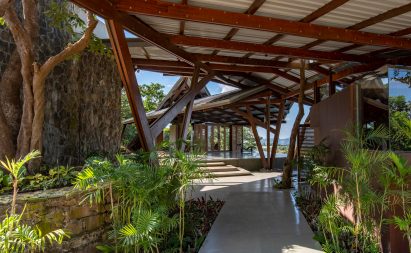 Paved terrace in a residential garden with an angular metal roof supported by a wooden structure