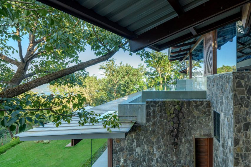 Exterior of a home with stone walls and an overhanding metal roof with a timber structure