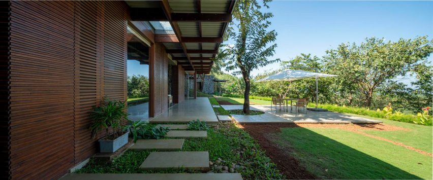 Exterior of a timber-clad home next to a grass garden with stone steps