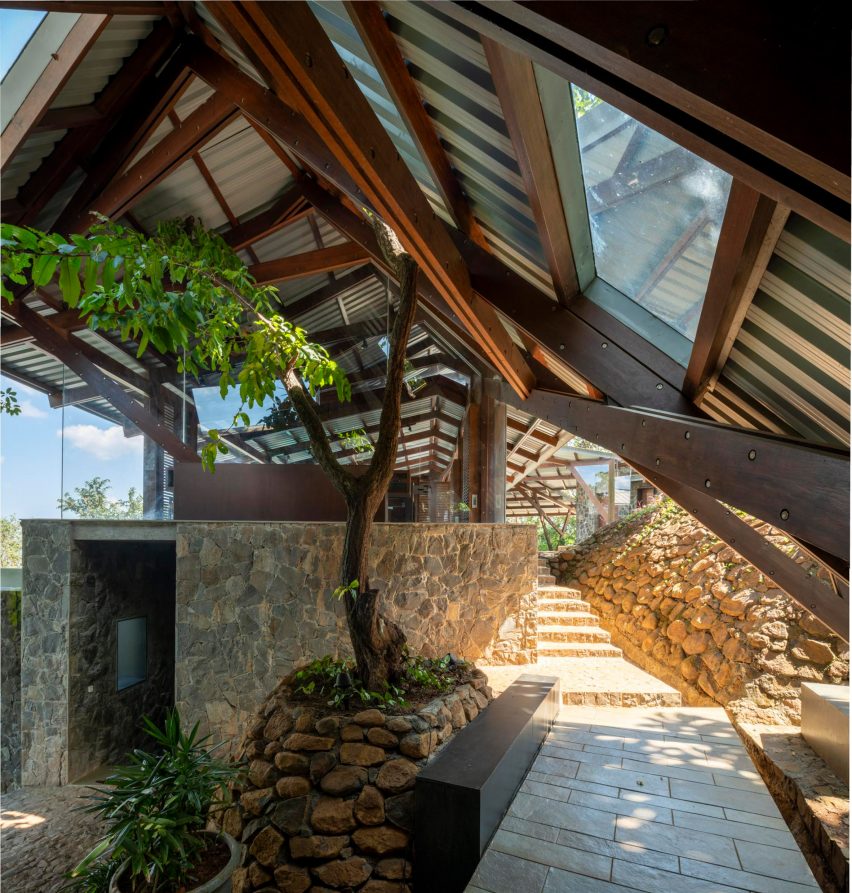 An outdoor space with sandy stone steps and a pitched metal roof with timber structure overhead
