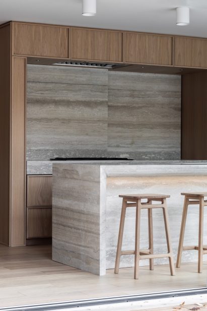 Storage hidden behind slab of travertine backsplash