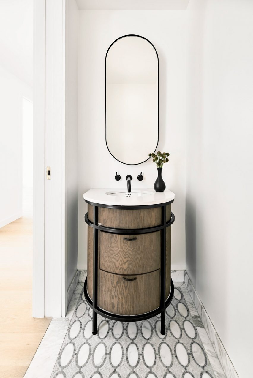 Interior of a small bathroom with a circular wood vanity and decorative floor tiling