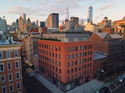 Exterior of the red-brick Grand Mulburry building by Morris Adjmi with a textured facade on a street corner in New York City