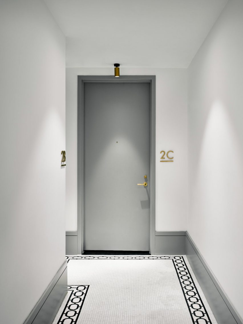 Apartment entrance hall with decorative floor boarder tiles, white walls and a grey door