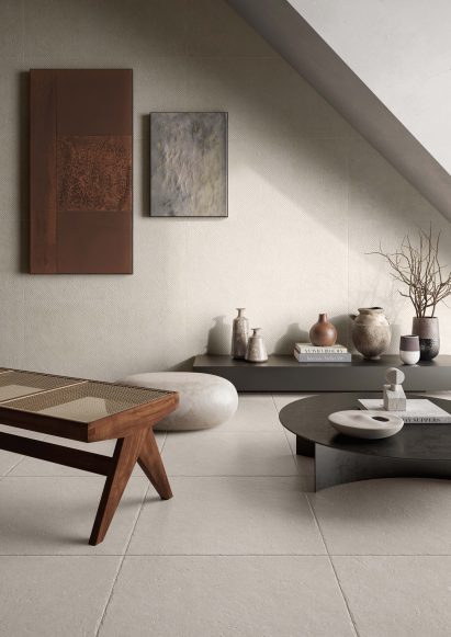 Corner of room with pale tiles on floor and walls and low, modern tables