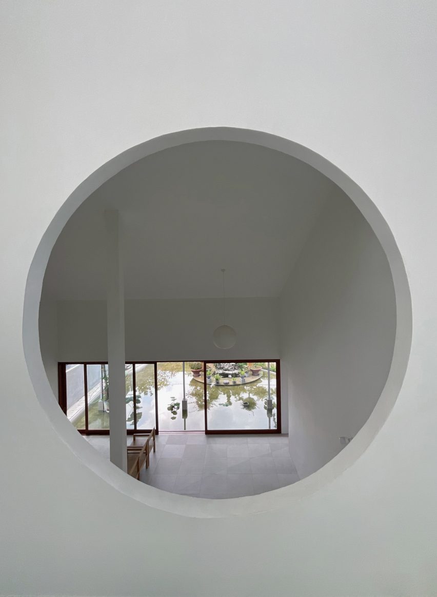 Circular window overlooking a living room with concrete floors and wooden furniture