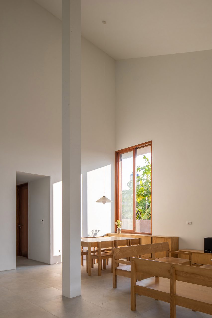 Interior double-height space with concrete flooring, white walls and wood furniture