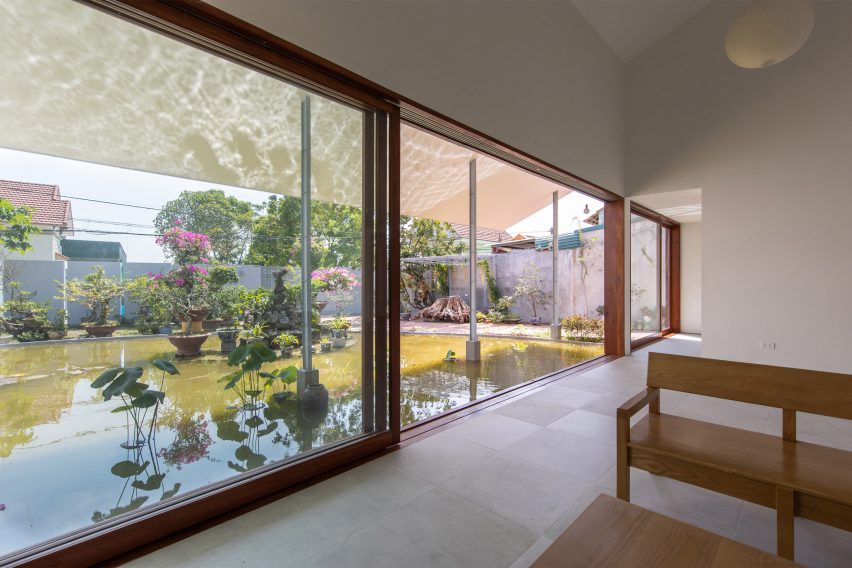 Interior space with concrete flooring, white walls and wood-framed sliding doors overlooking a pond