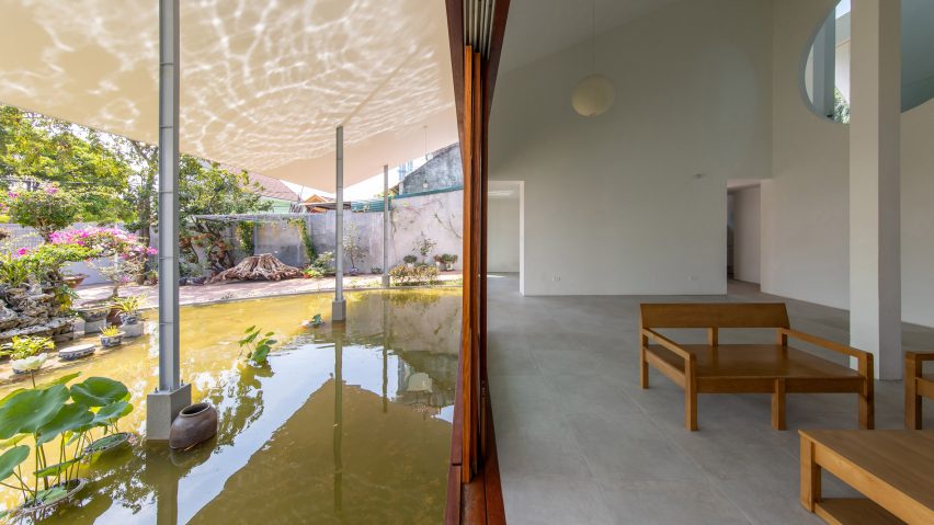 Wooden doorway dividing a concrete interior on one side and a covered outdoor space with a pond on the other side