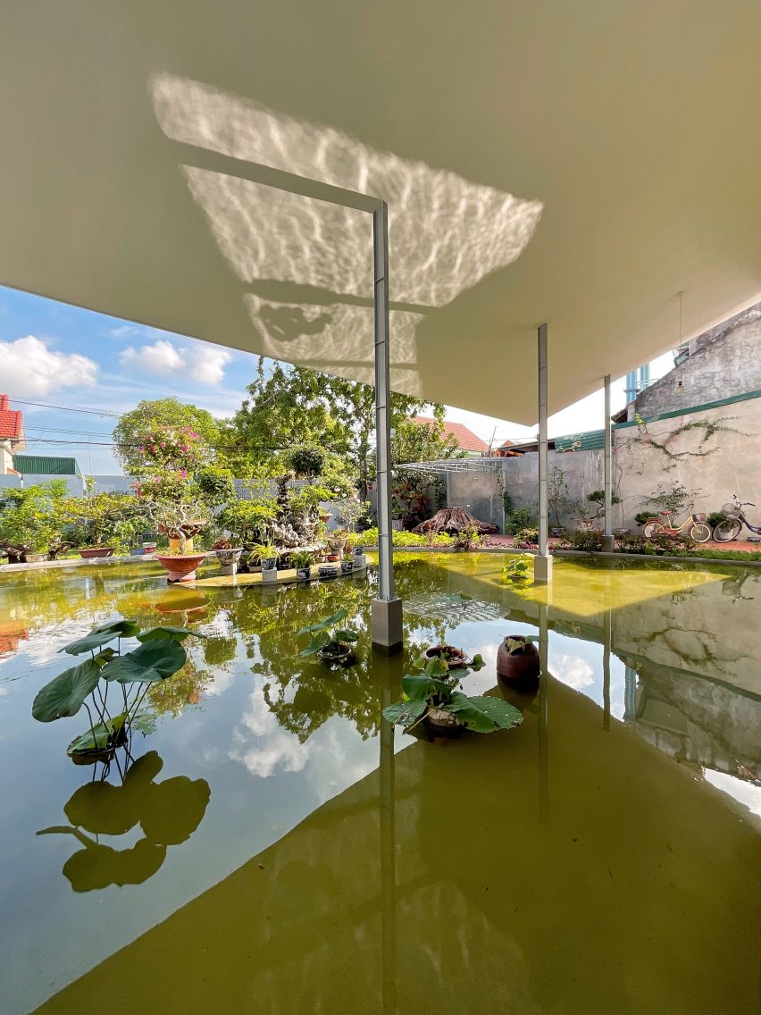 A pond with planting and a white roof supported by steel columns