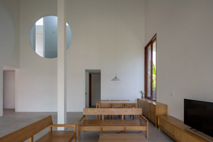 Interior space with concrete flooring, wood furniture, white walls and a circular window