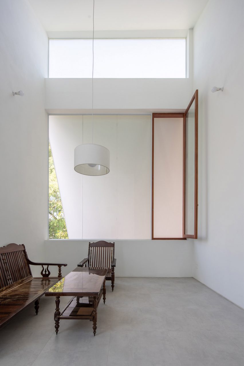 Interior space with concrete flooring, white walls, large square windows and dark wood furniture