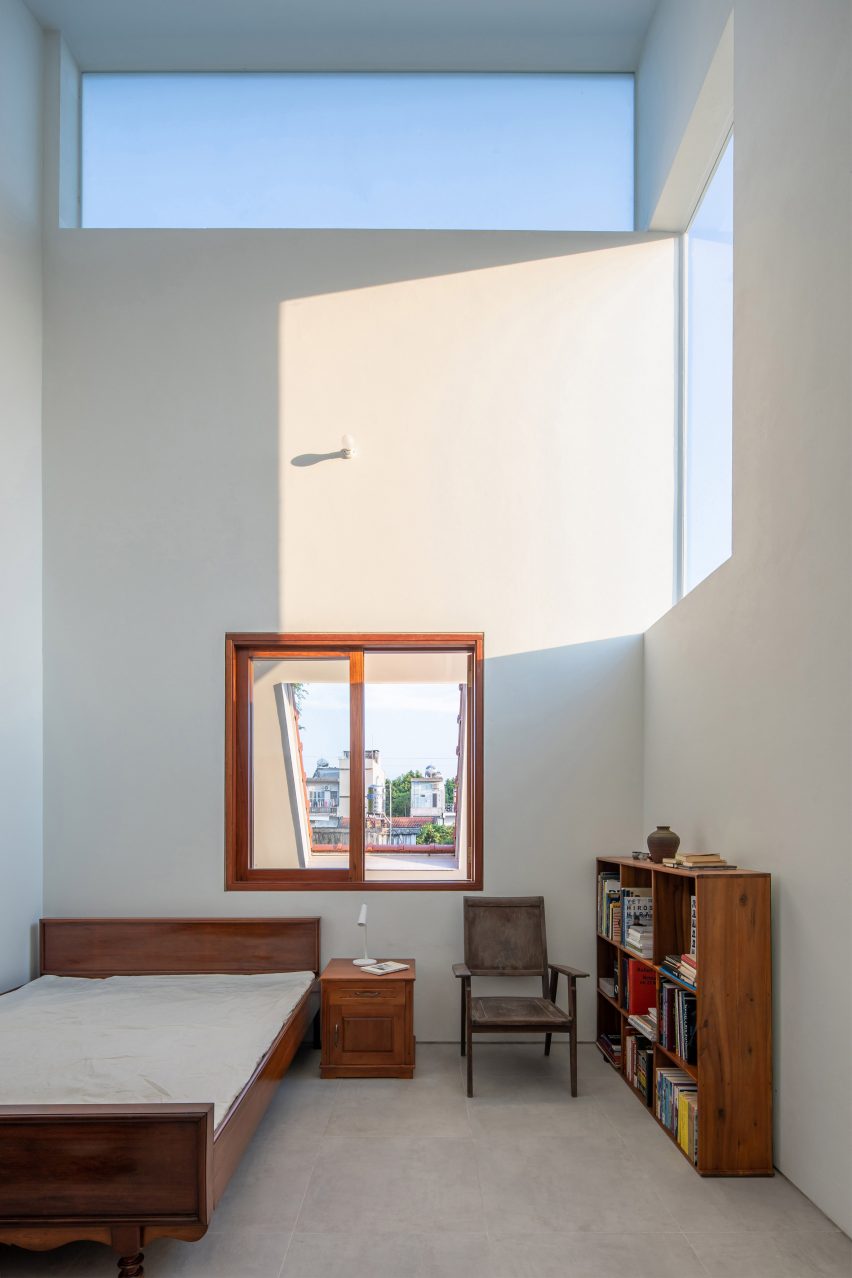 Bedroom with concrete flooring, white walls and dark wood furniture