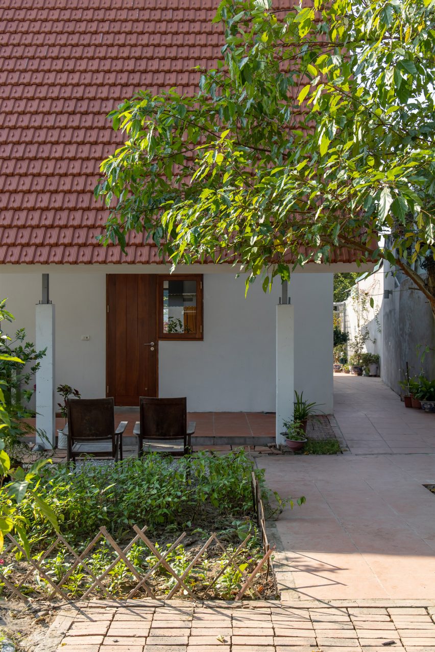 Outdoor paved patio with a square planted garden and a home with terracotta-tiled roof