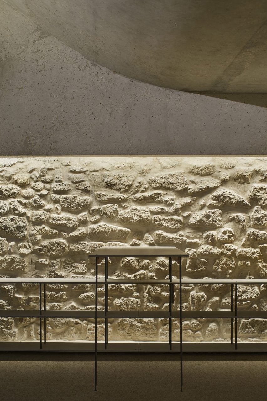 A room with a curved concrete ceiling, skylights and white brick walls