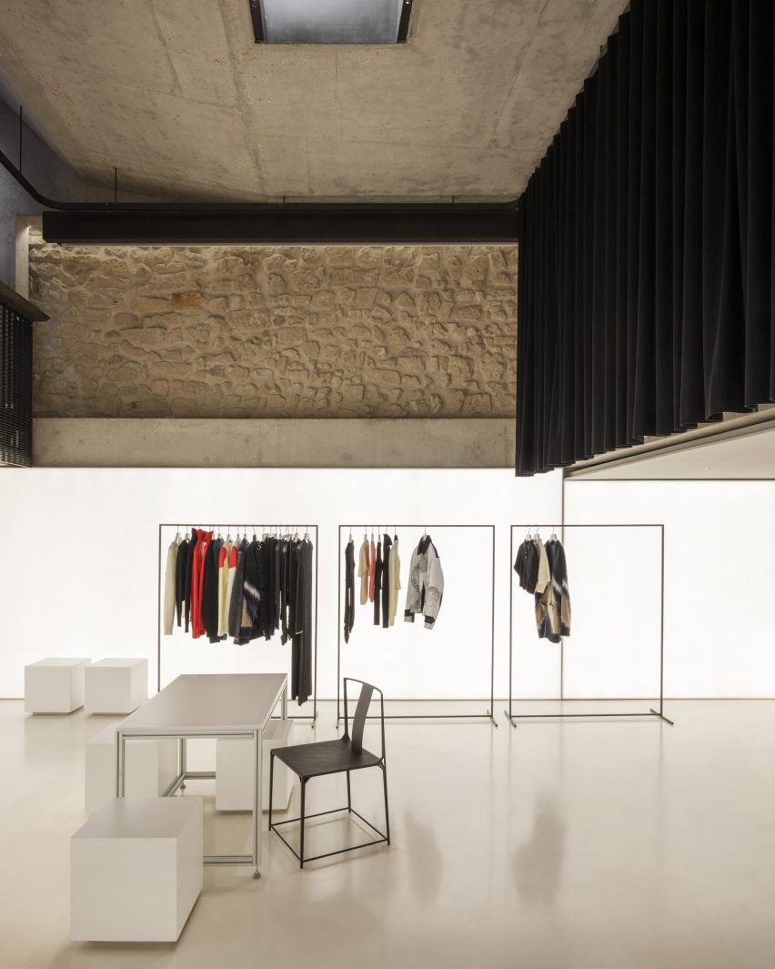 A retail showroom with white walls and floors and black curtains covering the upper parts of the walls