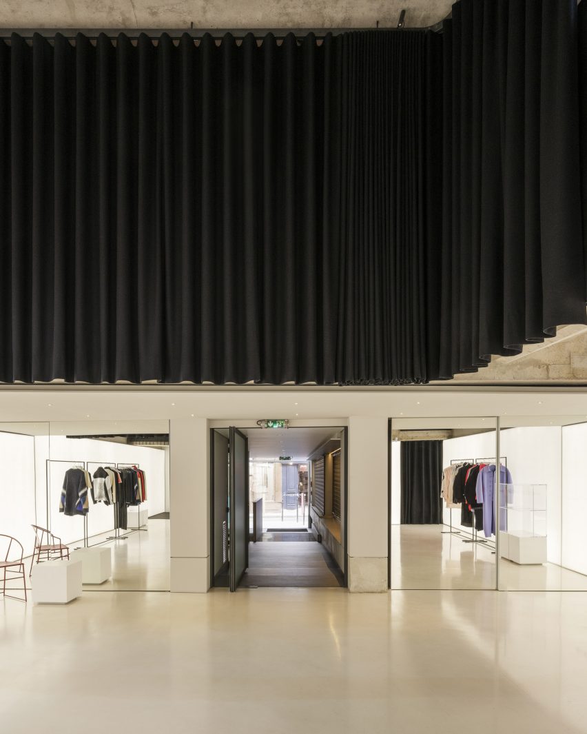 A retail showroom with white walls and floors and black curtains covering the upper parts of the walls