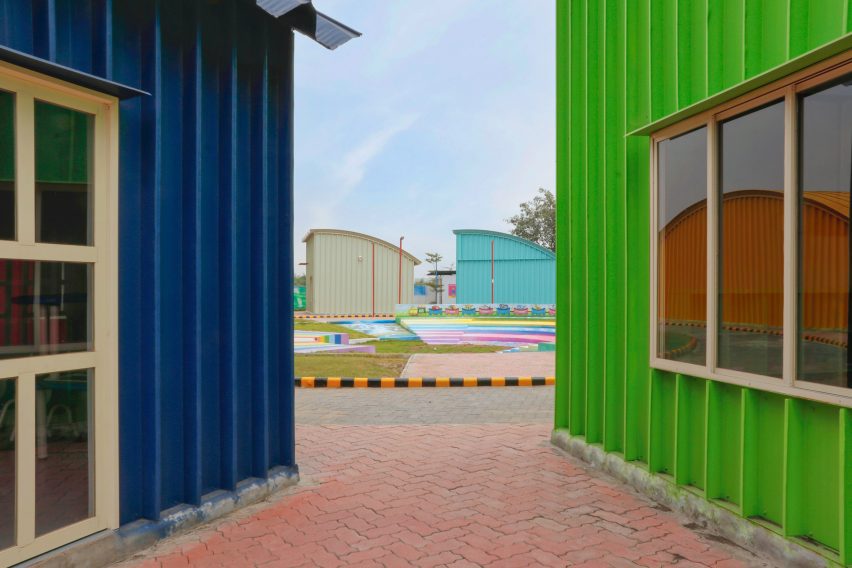 Green and blue steel school buildings on a paved walkway