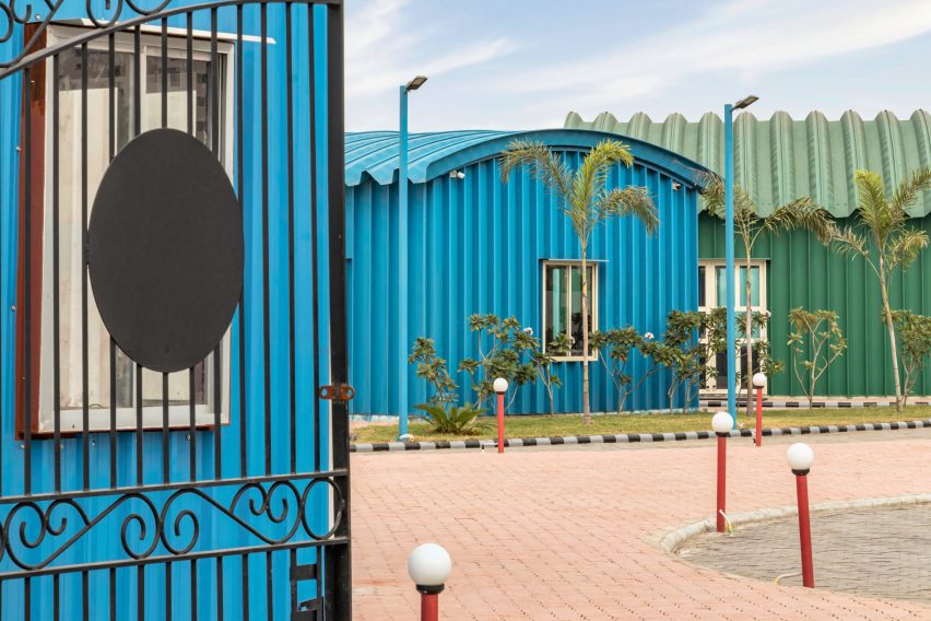Blue and green steel buildings next to a curved walkway
