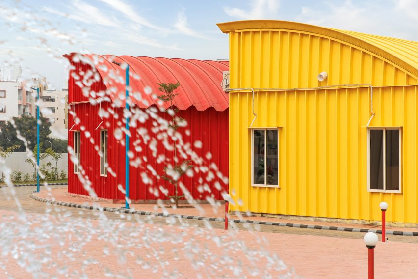 A water fountain in front of a red and yellow steel buildings