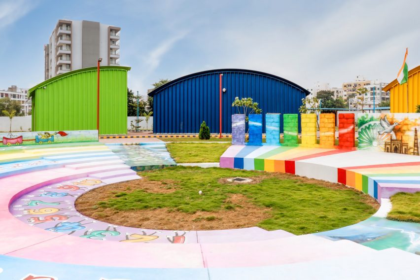 Colourful amphitheatre surrounded by green, blue and yellow steel buildings