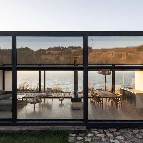 Exterior of a one-storey open-plan home with glazed walls overlooking the sea